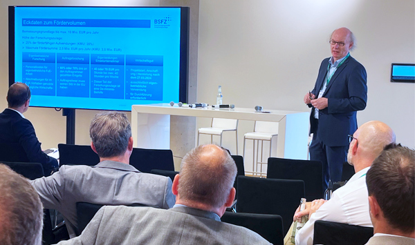 Dr. Andreas Hoffknecht steht vor einem Publikum und hält eine Präsentation