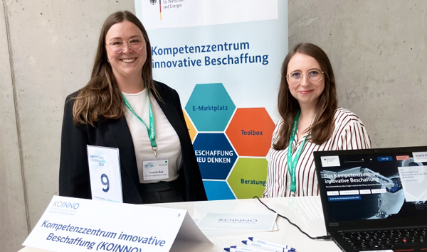 Zwei Frauen stehen am Stand von KOINNO und lächeln in die Kamera.