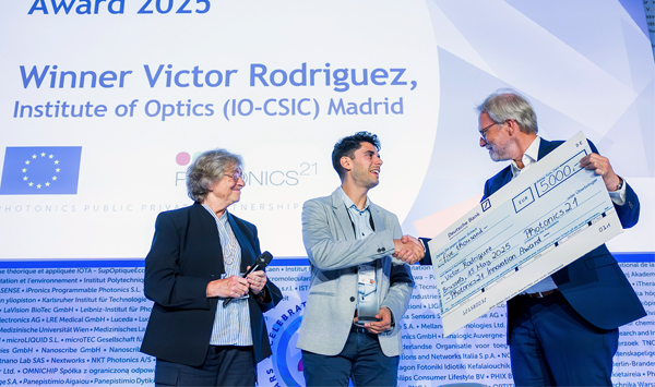 Ein Mann erhält einen übergroßen Scheck auf der Bühne im Rahmen des Photonics21 Innovation Awards.