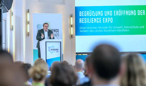 Oliver Krischer, Umweltminister des Landes Nordrhein-Westfalens, spricht auf der Bühne am Rednerpult.