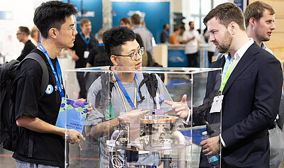 Drei junge Männer betrachten ein Ausstellungsexponat auf dem BMFTR-Messestand