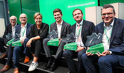 Die Gewinner der Innovationspreises NRW 2025 halten ihre Auszeichnung in die Kamera.